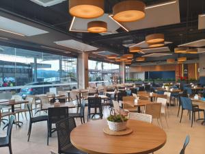 a restaurant with wooden tables and chairs and windows at Hotel 28 Embu das Artes in Embu