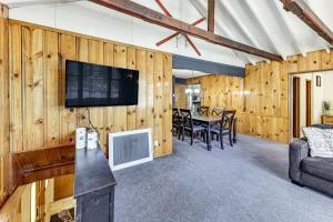 ein Wohnzimmer mit Holzwänden, einem TV und einem Tisch in der Unterkunft Swim, Ski and Explore Cabin in Green Valley Lake! in Green Valley Lake