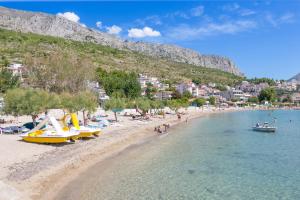 a beach with boats on the water and a town at Apartments and rooms by the sea Duce, Omis - 2746 in Duće