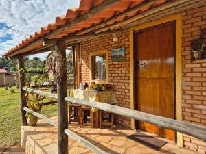 a brick house with a wooden door and a fence at Chalés Mirante da Serra in São Thomé das Letras