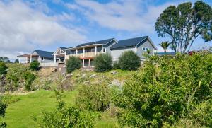 a house on top of a hill with grass at The View - Over the Bay in Kerikeri