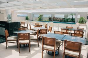 a restaurant with tables and chairs and a pool at Apart Hotel Diamond Flat Casal in Nova Iguaçu