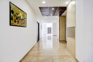 a hallway with white walls and a painting on the wall at Hotel O SR Farm in Bodakdev