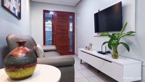 a living room with a tv and a vase on a table at Casa Luz Caruaru - próx feira da sulanca in Caruaru