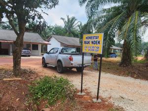 a truck parked on a dirt road with a sign at Homestay Mak 'Ndek '6' in Tangkak +4 photos