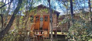 a cabin in the woods with a table and chairs at Rey Sol Reina Luna in Lago Puelo