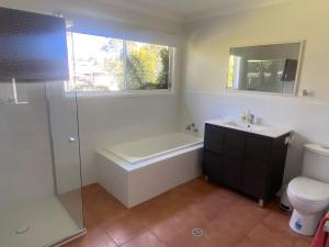 a bathroom with a tub and a sink and a toilet at 6 Wrights Close, Mallacoota in Mallacoota