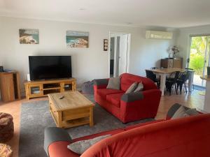 a living room with a red couch and a television at 6 Wrights Close, Mallacoota in Mallacoota