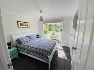 a white bedroom with a bed and a window at 6 Wrights Close, Mallacoota in Mallacoota