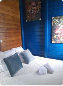 a bed with two pillows and a blue wall at Villabadlou Ti-Colibri in Trois-Rivières