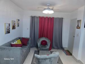 - un salon avec un canapé et un rideau rouge dans l'établissement Peaceful Cottage, à Santiago de los Caballeros