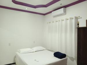 a bedroom with a white bed and a white curtain at Casa grande, ar em todos os quartos, cabe 3 carros in Barra do Garças