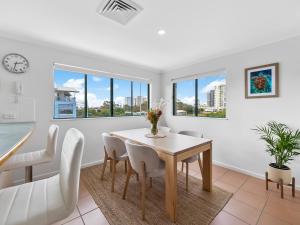 ein Esszimmer mit Tisch und Stühlen und Fenstern in der Unterkunft Sea Shapes Coastal Escape 3 Bed Apartment in Maroochydore
