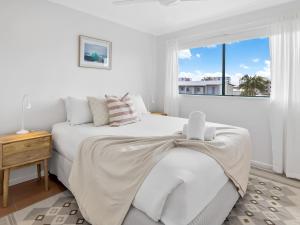 ein weißes Schlafzimmer mit einem Bett und einem Fenster in der Unterkunft Sea Shapes Coastal Escape 3 Bed Apartment in Maroochydore + 5 Fotos