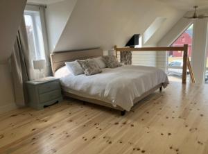 a bedroom with a bed and a wooden floor at Luxury oceanfront escape in Neguac