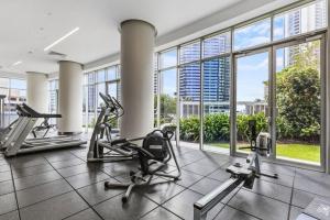 Un gimnasio con cintas de correr y elípticas en un edificio con ventanas. en Level 15 - Hilton Surfers Paradise, en Gold Coast