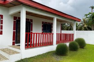 a small white house with a red fence at La Maison Du Voyageur in Kribi