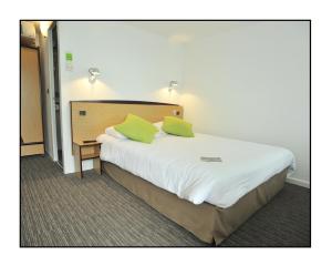 Un dormitorio con una cama grande con dos almohadas verdes. en Kyriad Châlons-En-Champagne - Saint-Martin, en Châlons-en-Champagne