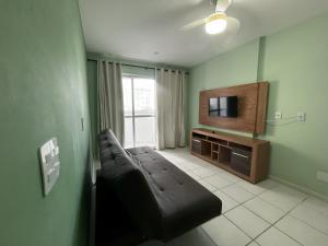a living room with a couch and a flat screen tv at Guarapari Residence com piscina sauna e ar in Guarapari