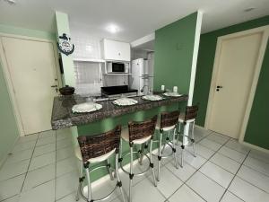 a kitchen with green walls and a counter with bar stools at Guarapari Residence com piscina sauna e ar in Guarapari