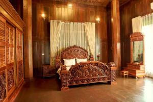 a large bed in a room with wooden walls at Heritage Village Resort in Kampot