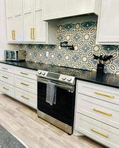 een keuken met witte kasten en een zwarte oven bij Deluxe Fun House - Pet Friendly in Piney +44 foto's