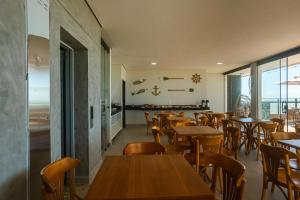 a restaurant with wooden tables and chairs and windows at Almaré Pousada Exclusiva in Maragogi
