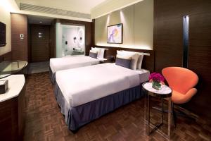 a hotel room with two beds and a chair at Nina Hotel Island South in Hong Kong +28 photos