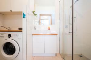 Un baño blanco con lavabo y lavadora. en Awesome Beach House Bicheno, en Bicheno