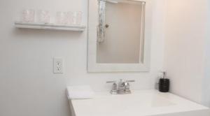 a white bathroom with a sink and a mirror at Comfortable Two Bedroom Basement Suite with Full Kitchen Bathroom and Queen Beds in Richmond Hill