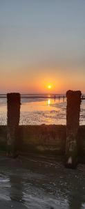a sunset over the ocean with people in the water at Rūm by the beach in Camber +10 photos
