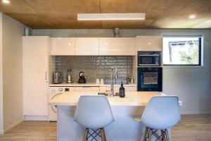 Una cocina con gabinetes blancos y dos taburetes de bar. en No3onfraser, en Twizel