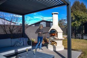 Una mujer parada junto a una chimenea en un patio trasero. en No3onfraser, en Twizel