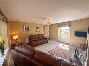a living room with a leather couch and a television at Peace Cottage in Darlington