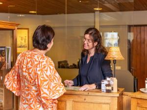 a woman standing at a counter talking to a woman at Brabant Retreat Close to Tilburg in Westelbeers +27 photos