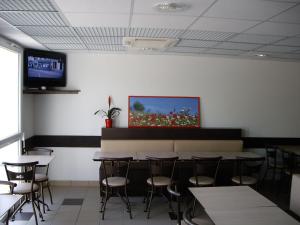 uma sala de jantar com mesas e cadeiras e uma televisão na parede em Ace Hotel Brive em Brive-la-Gaillarde