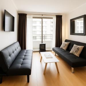 a living room with a black couch and a table at Steps from the subway and Free Parking in Santiago