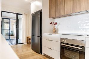 una cocina con nevera de acero inoxidable y armarios blancos en Spacious and Convenient - Azure Retreat, en Bicheno 22 fotos más