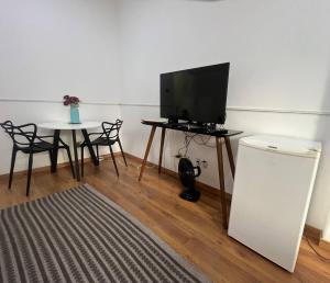 een woonkamer met een televisie en een tafel met stoelen bij Loft no Centro- Lapa, Consulado, Praia,Metrô e AR! 605 in Rio de Janeiro +1 foto