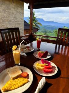 a wooden table with plates of breakfast foods and drinks at Villas Ume Sedani in Sidemen