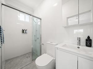 a white bathroom with a toilet and a sink at The Fletcher Bondi in Sydney +53 photos