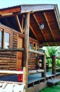 a log cabin with a porch and a roof at El Durazno Apart Hotel y Cabañas in San Pedro