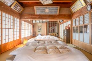 a group of four beds in a room with windows at 岐阜羽島の隠れ家 古民家cocone in Hashima