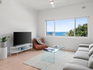 a living room with a couch and a glass table at The Fletcher Bondi in Sydney