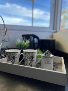 three coffee mugs in a tray on a counter at Excelente propiedad in La Porteña