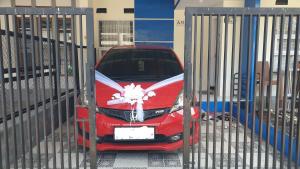 a red car is parked behind a gate at Homestay A51 in Panjalu +1 photo