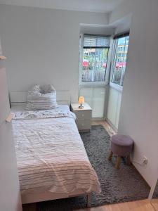 a bedroom with a bed and a stool and two windows at EBE-Connect in Ebersberg