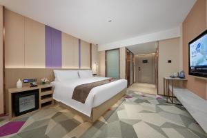 a bedroom with a large bed and a flat screen tv at Lavande Hotels Guangzhou Panyu Hanxi Changlong Dashi Subway Station in Guangzhou