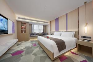 a bedroom with a large white bed and a television at Lavande Hotel Guangzhou Panyu Hanxi Changlong Dashi Subway Station in Guangzhou