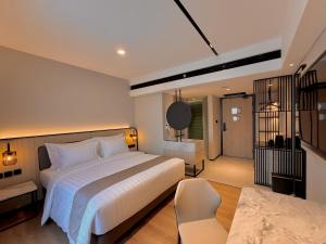 a bedroom with a large white bed and a chair at FortunaSuites Malioboro Yogyakarta in Sentool +41 photos
